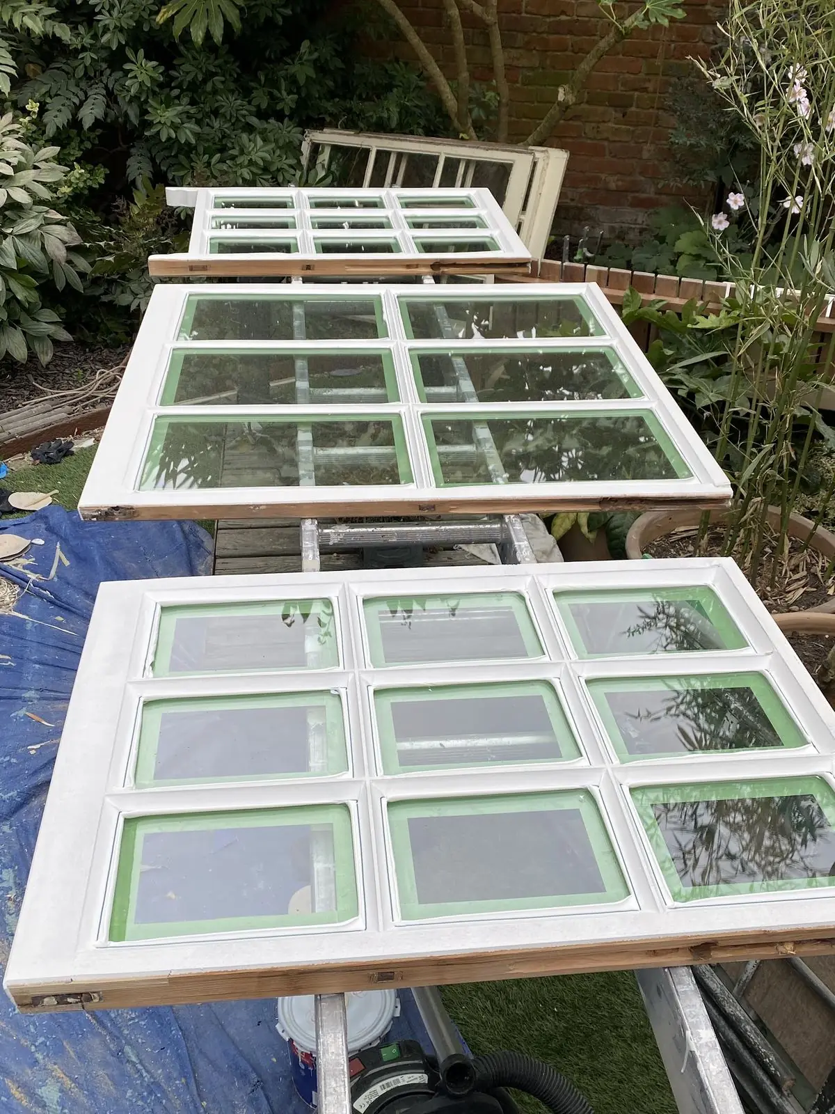 Refurbished sash panels with new vacuum-insulated glass units installed, drying outside on supports