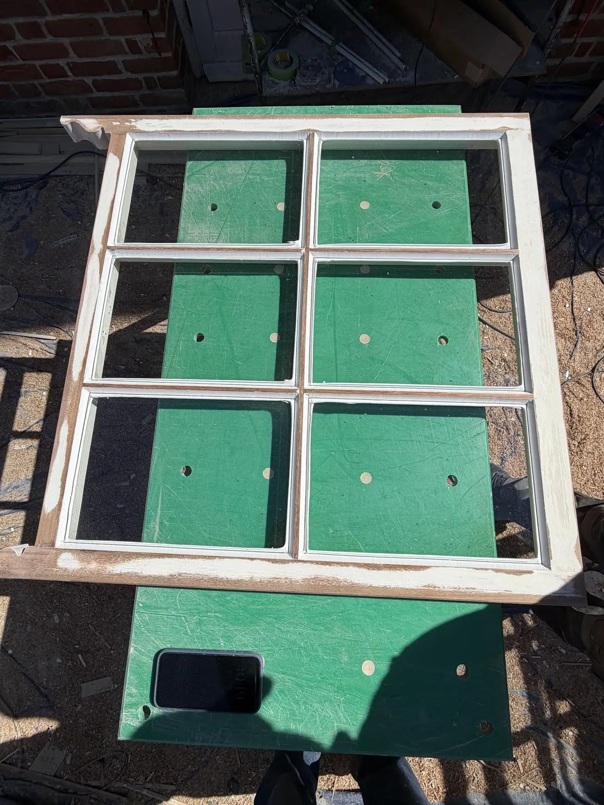 A six-pane sash on the workshop bench with the glass removed, glazing bars exposed and the meeting rail visible — about to be routed for the brush-pile gasket