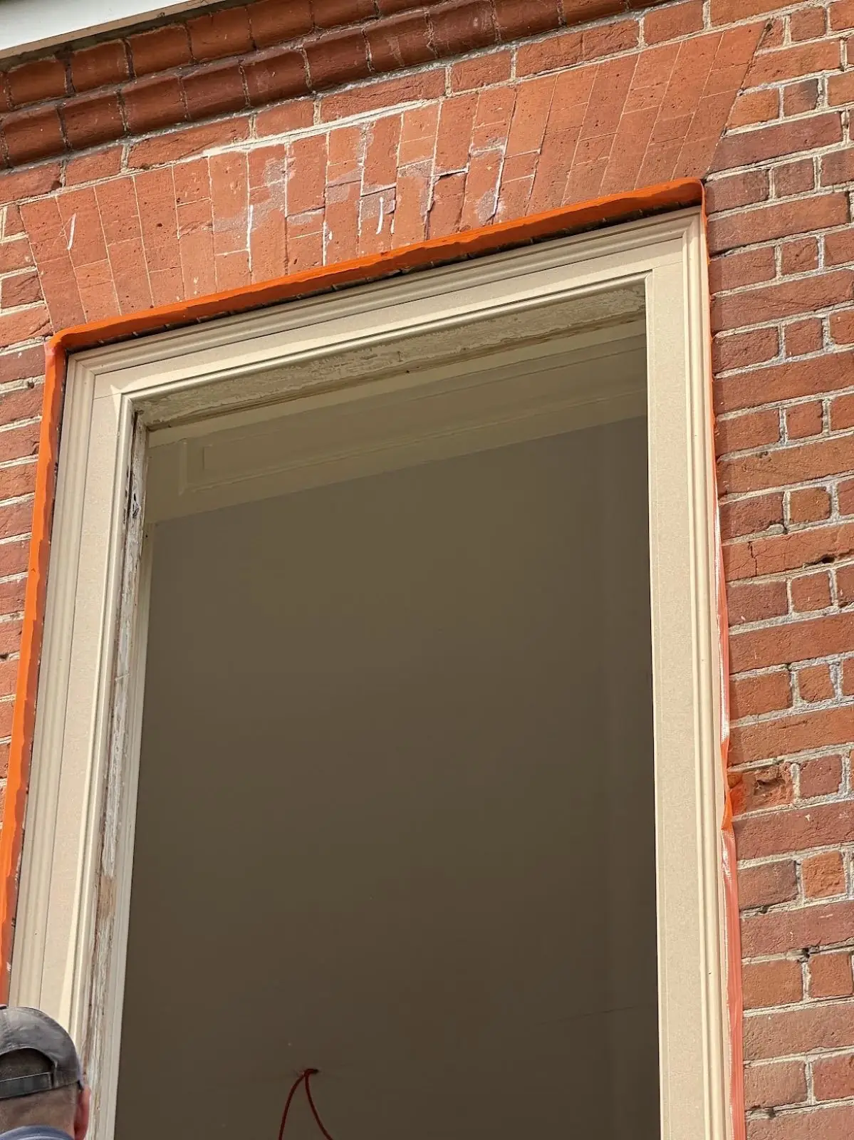 Sash window with orange masking tape around the brick reveal, mid-restoration