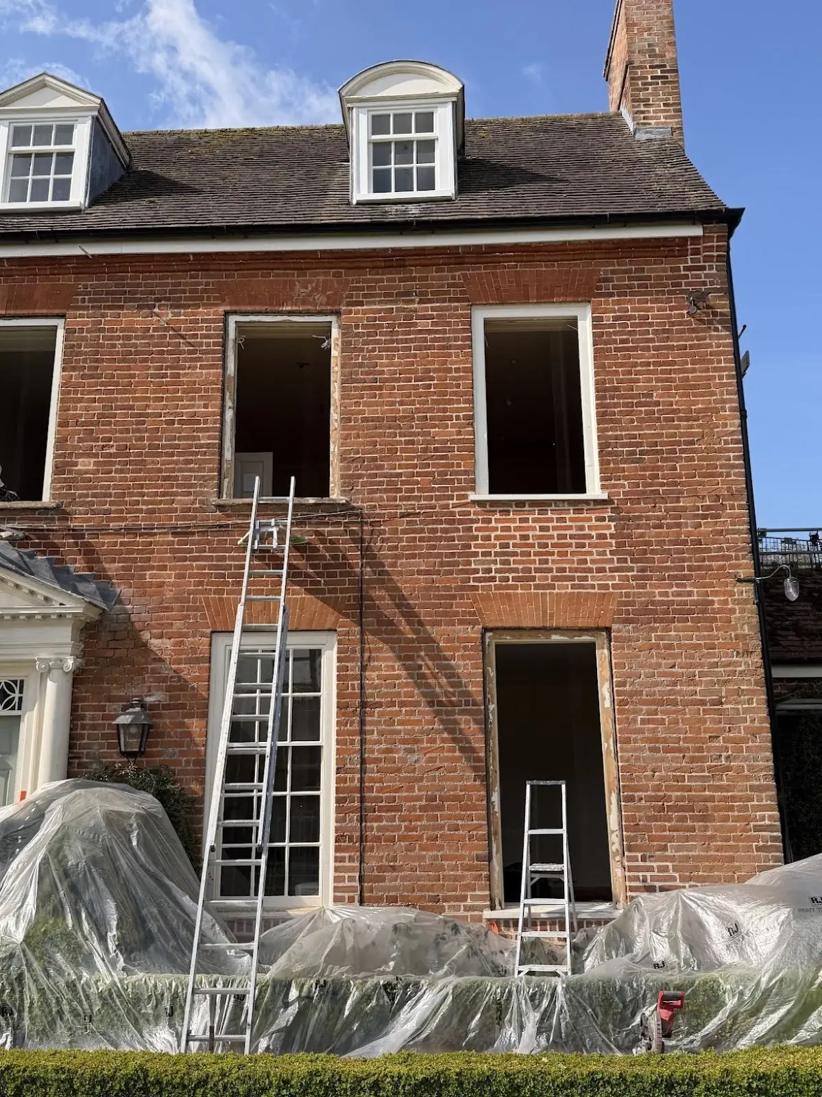 Period brick house with upper-floor sash windows removed, ladders in place
