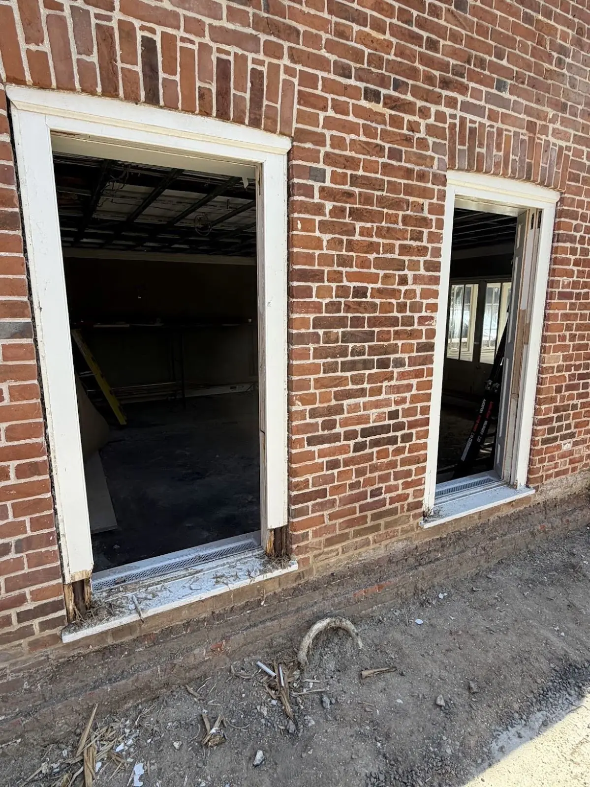 Two ground-floor window openings with sashes removed, exposed timber visible