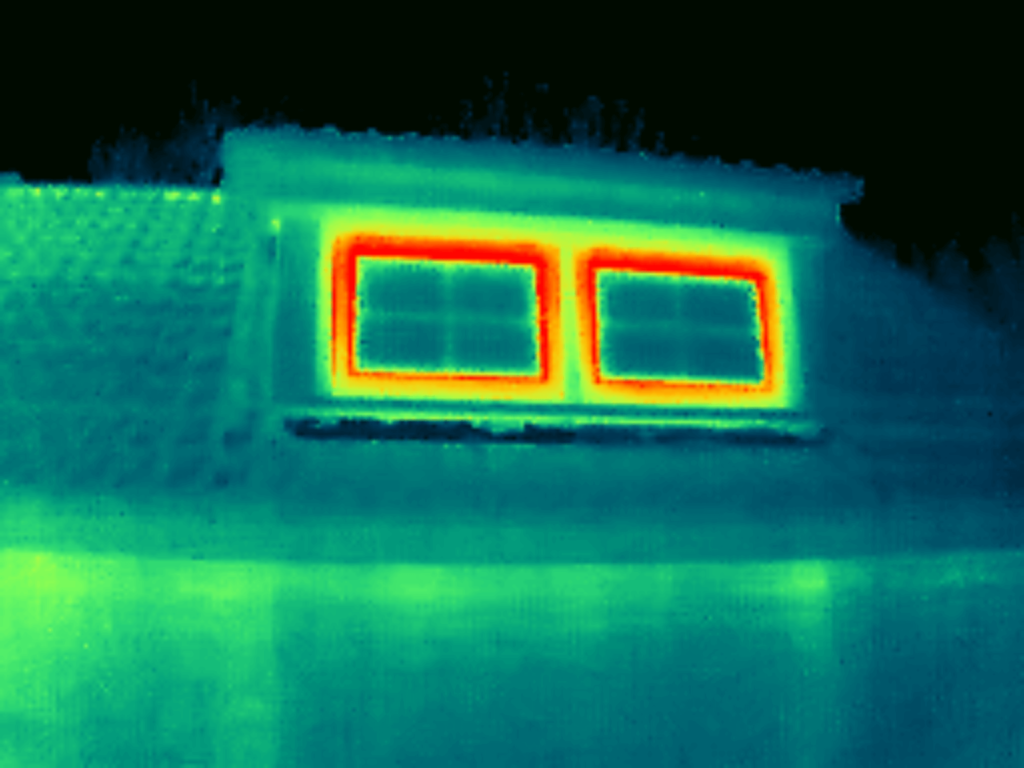 A thermal image of a building's roof reveals two rectangular windows emitting heat in vibrant red and yellow, hinting at potentially high U-values for windows.