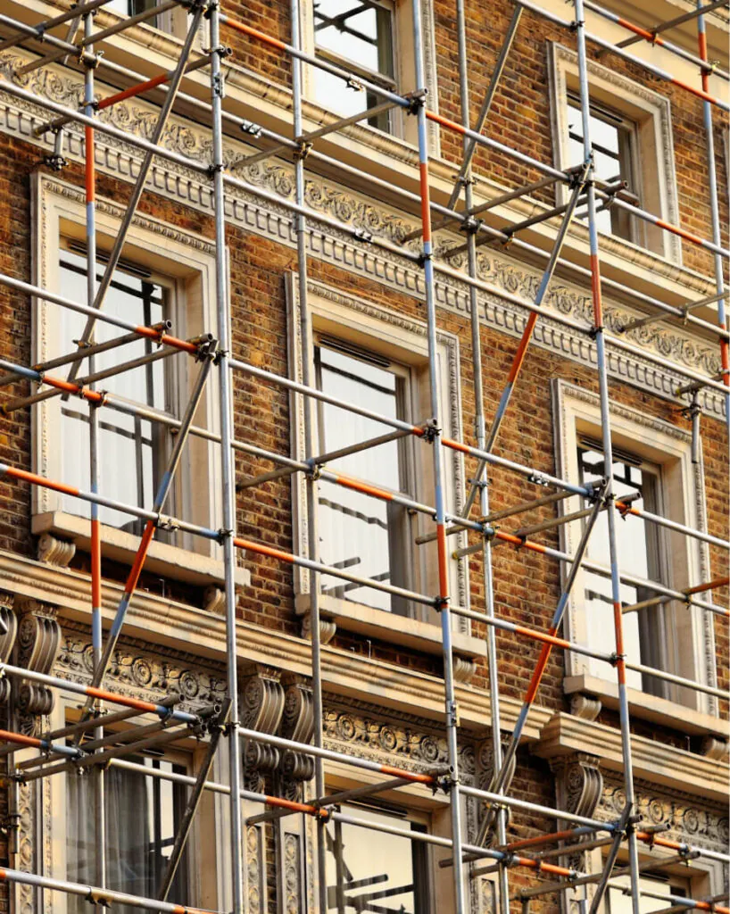 Scaffolding covers the facade of a brick building with ornate detailing and multiple windows, hinting at a sash window refurbishment to preserve its historic charm.